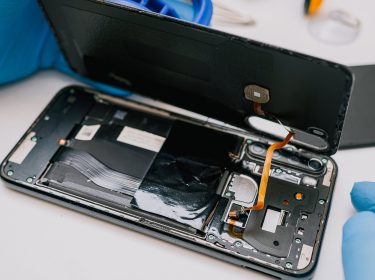 Auf diesem Bild ist zu sehen, wie ein Smartphone fachmännisch geöffnet wird – ein typisches Szenario, wenn das Handy kaputt ist und geprüft wird, ob eine Garantie greift.