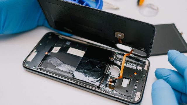 Auf diesem Bild ist zu sehen, wie ein Smartphone fachmännisch geöffnet wird – ein typisches Szenario, wenn das Handy kaputt ist und geprüft wird, ob eine Garantie greift.