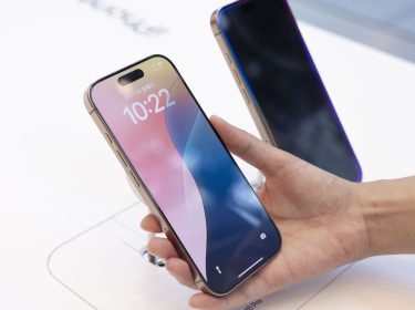 Hand hält im Apple Store ein iPhone 16 Pro in die Kamera.