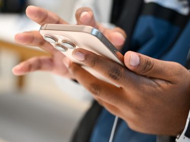 Eine Person hält ein iPhone in der Hand.