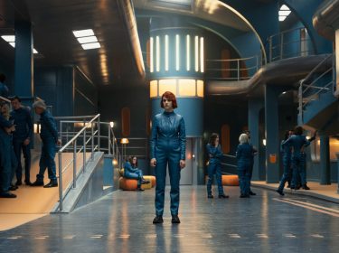 Asia (Alicia Falcó) steht im Bunker, im Hintergrund weitere Bewohner.