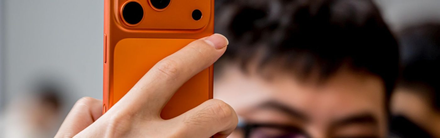 Hand hält das orange iPhone 17 Pro in die Kamera.