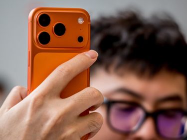 Hand hält das orange iPhone 17 Pro in die Kamera.