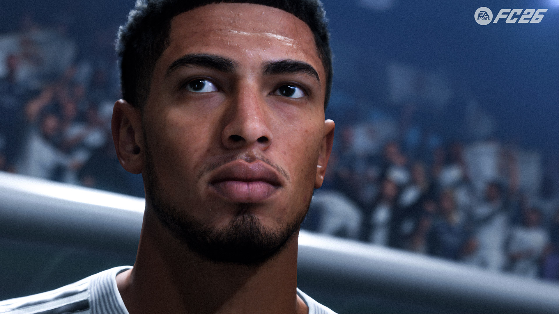 Auf diesem Screenshot aus EA FC 26 ist der englische Fußballspieler Jude Bellingham in einer fotorealistischen Darstellung zu sehen. Er blickt fokussiert nach oben, im Hintergrund jubelt unscharf das Stadionpublikum. Das Bild symbolisiert seinen hohen Rang unter den besten EA FC 26-Spieler:innen und fängt eine konzentrierte, professionelle Spielatmosphäre ein.