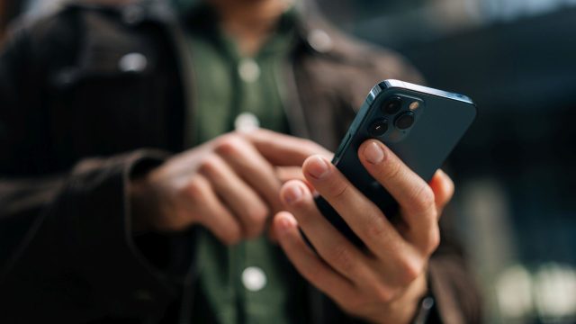 Mann tippt auf ein iPhone.