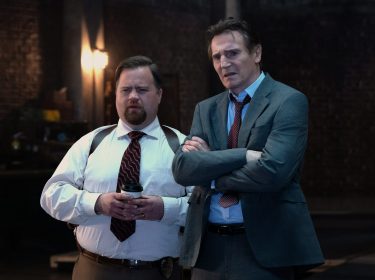 In den GigaTV-Highlights im Oktober 2025 siehst du eine Szene aus dem Film „Die nackte Kanone“, in der Liam Neeson als Frank Drebin Jr. und Paul Walter Hauser als Ed Hocken Jr. nebeneinander stehen. Beide blicken ernst und leicht verwirrt nach vorne.