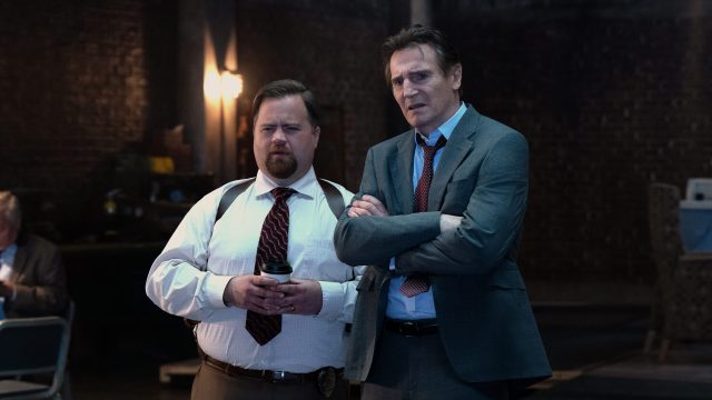 In den GigaTV-Highlights im Oktober 2025 siehst du eine Szene aus dem Film „Die nackte Kanone“, in der Liam Neeson als Frank Drebin Jr. und Paul Walter Hauser als Ed Hocken Jr. nebeneinander stehen. Beide blicken ernst und leicht verwirrt nach vorne.