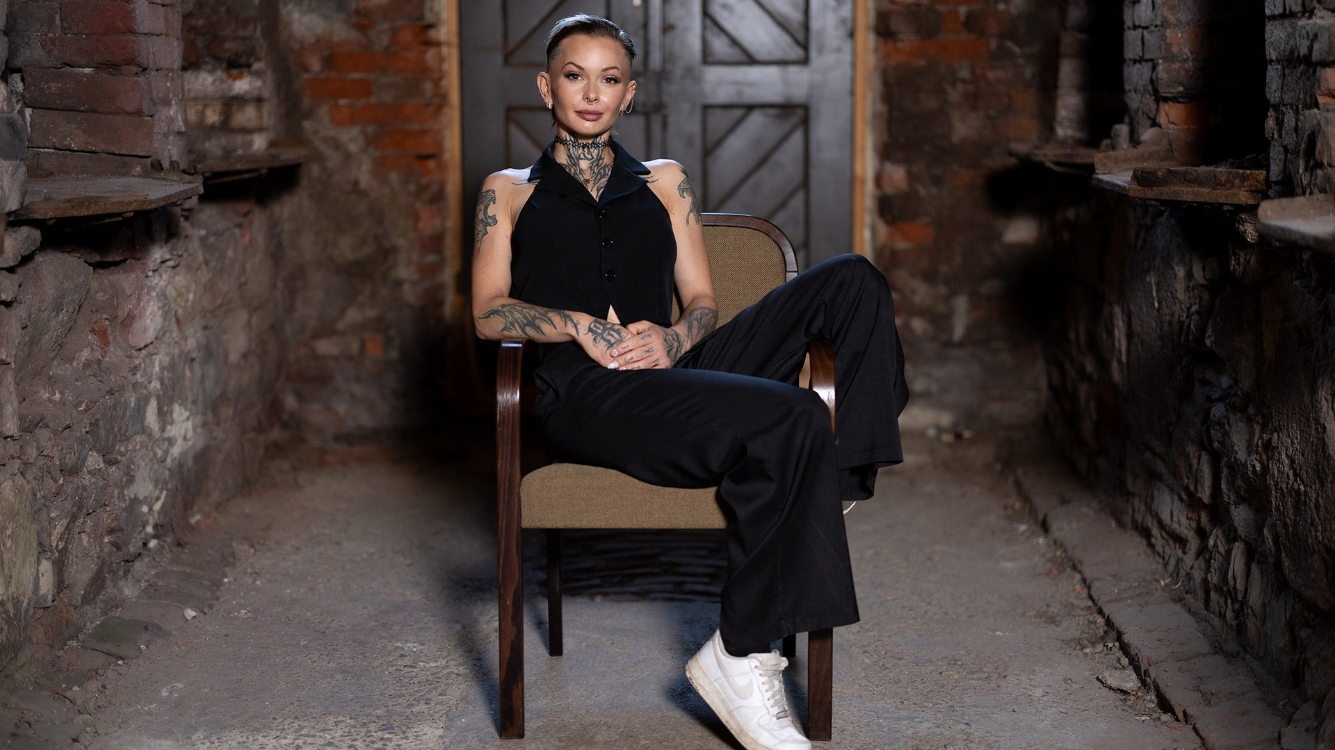 Edith Stehfest ist auf dem Bild zu „Das große Promi-Büßen“ 2025 in einem schwarzen, ärmellosen Outfit zu sehen und sitzt lässig in einem Holzsessel.