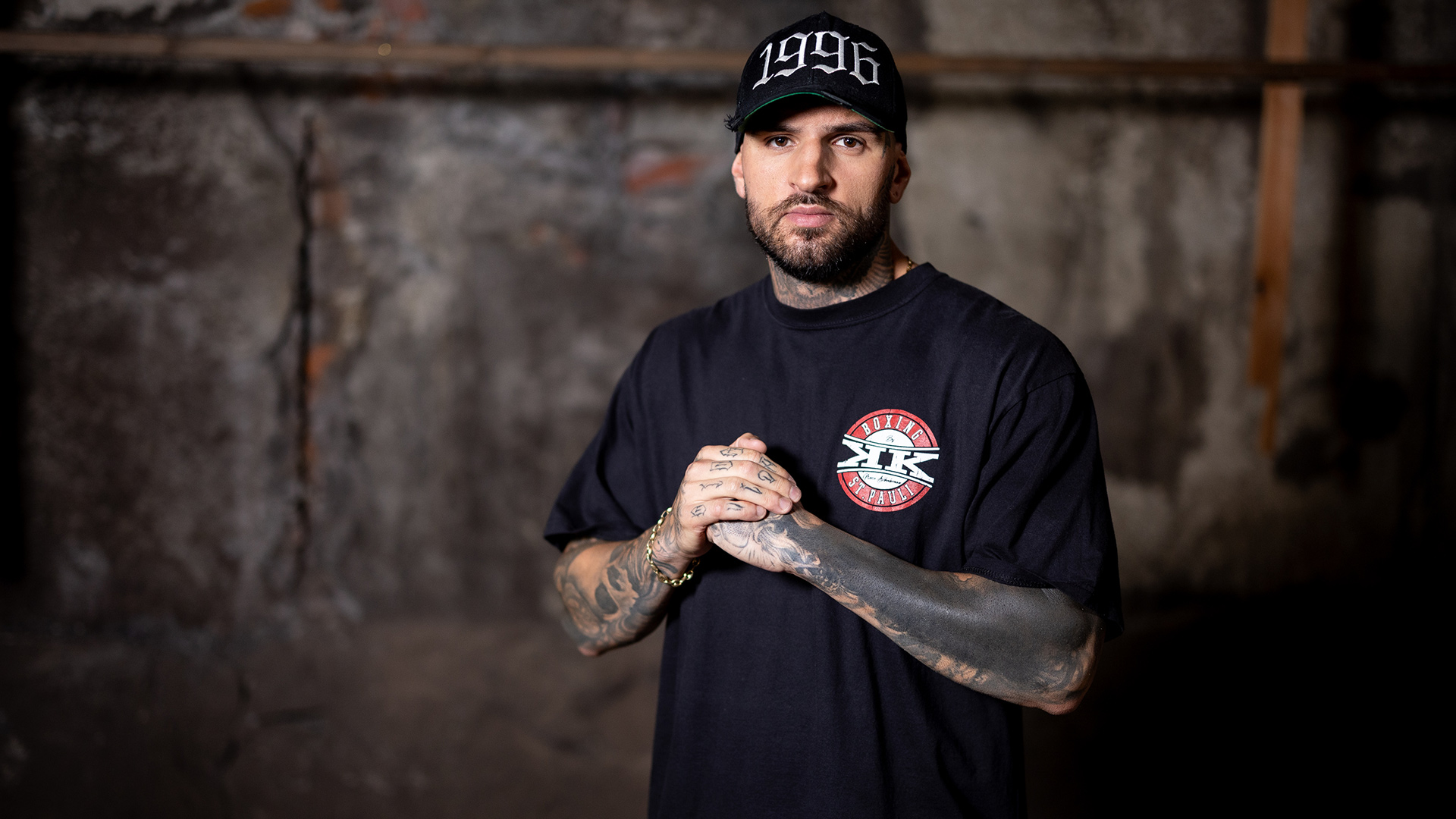 Diogo Sangre trägt auf dem Bild zu „Das große Promi-Büßen“ 2025 ein schwarzes T-Shirt und eine Cap mit der Jahreszahl 1996.