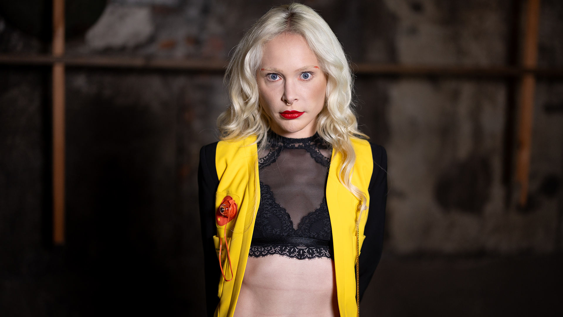 Theresia Fischer blickt auf dem Bild zu „Das große Promi-Büßen“ 2025 in die Kamera. Sie trägt ein gelb-schwarzes Outfit mit transparentem Spitzentop.