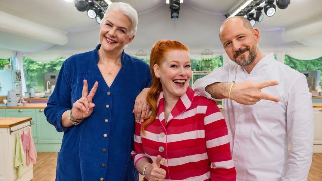 Moderatorin Enie van de Meiklokjes und die Juroren Bettina Schliephake-Burchardt und Christian Hümbs posieren in der Backstube.