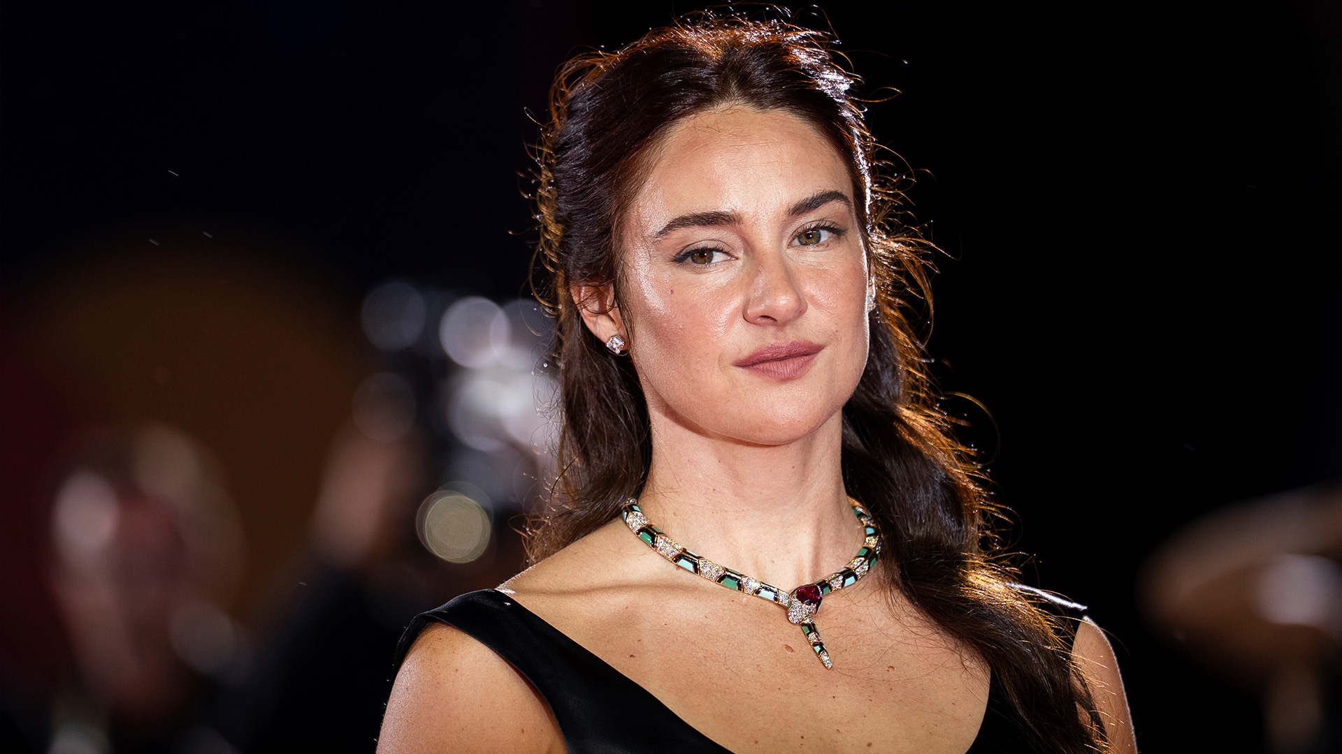 Auf diesem Bild zur Count My Lies-Serie ist Schauspielerin Shailene Woodley in einem eleganten, schwarzen Kleid mit funkelnder Schlangenkette zu sehen. Sie blickt ruhig und selbstbewusst in die Kamera. Der Hintergrund ist unscharf und deutet auf ein Event hin, aber der Fokus liegt klar auf ihrer Erscheinung.