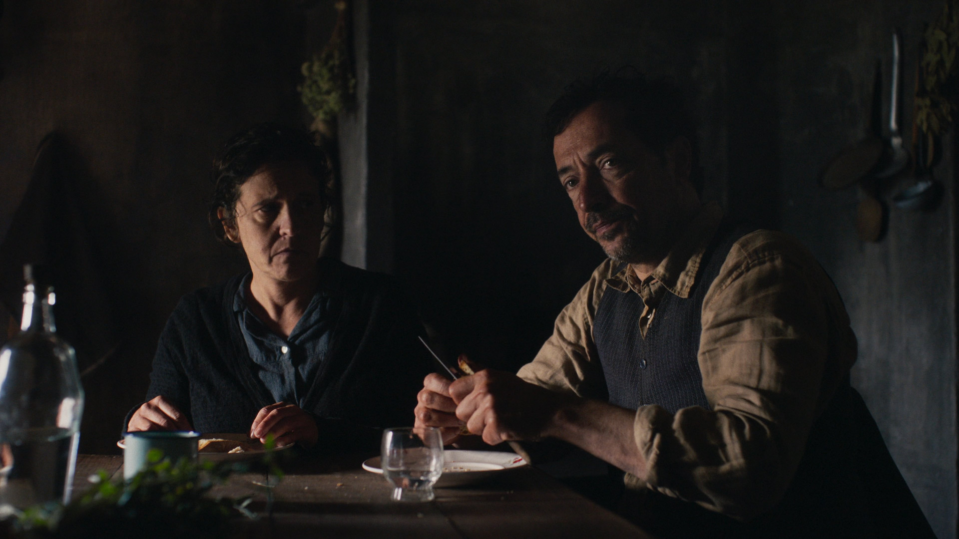 Auf dem Bild zu den internationalen Sendern und TV-Paketen bei Vodafone ist eine Szene aus der portugiesischen Serie „Finisterra“ zu sehen. Zwei Personen sitzen in einem spärlich beleuchteten Raum an einem Holztisch, umgeben von einfachen Gegenständen.