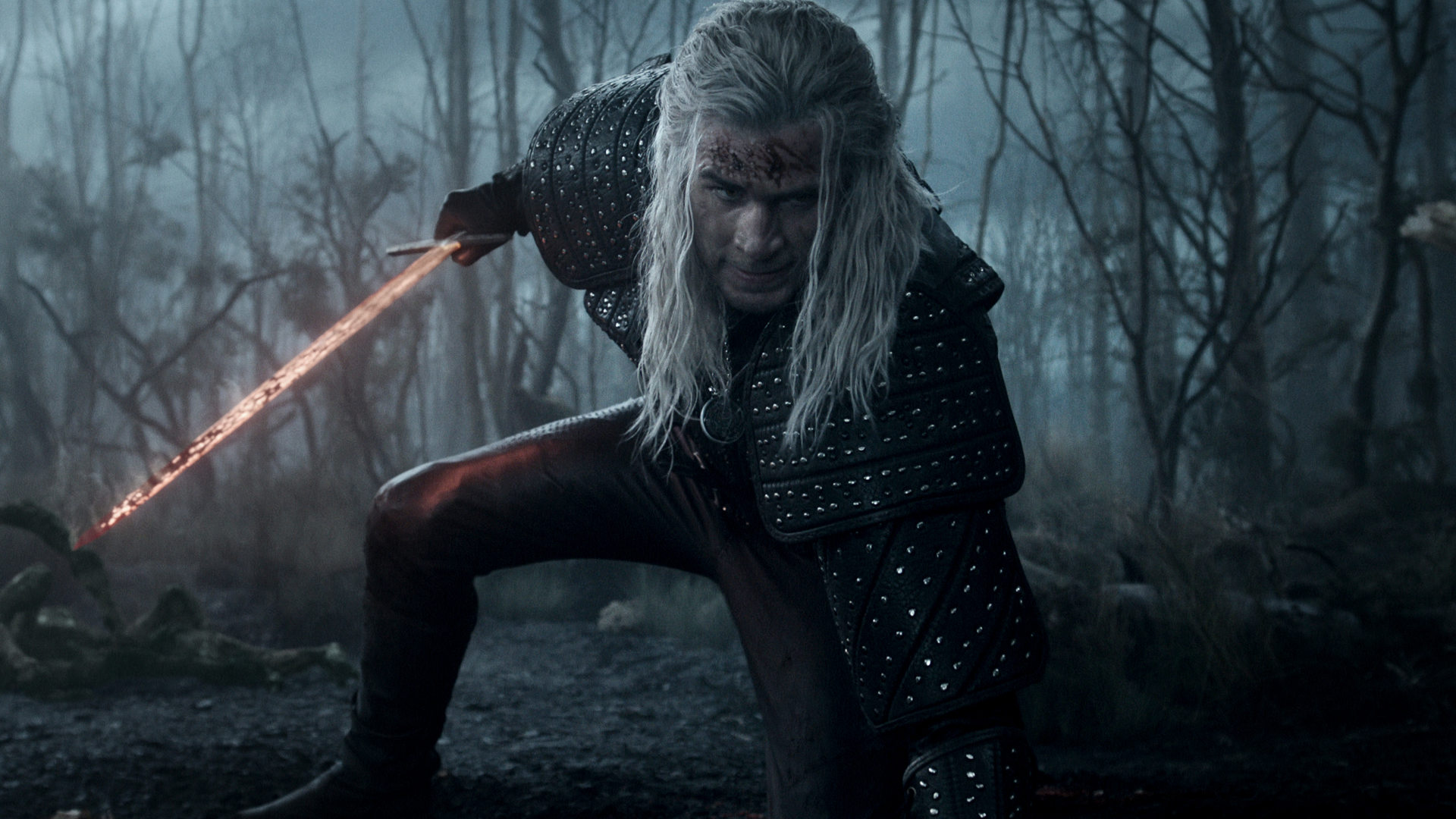 Liam Hemsworth kniet als Geralt von Riva auf dem Boden und schaut in die Kamera - in der Hand ein Schwert.