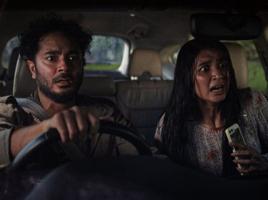 Ein Mann und eine Frau starren geschockt aus dem Auto heraus.