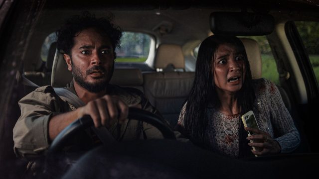 Ein Mann und eine Frau starren geschockt aus dem Auto heraus.