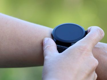 Mann berührt mit seiner Hand eine Smartwatch auf seinem Arm.