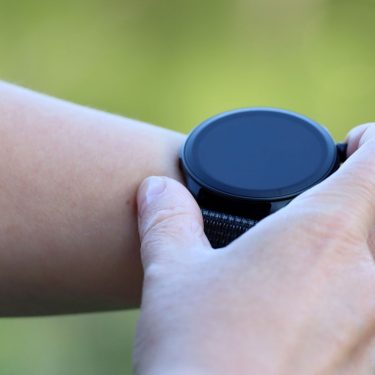 Mann berührt mit seiner Hand eine Smartwatch auf seinem Arm.