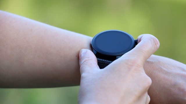 Mann berührt mit seiner Hand eine Smartwatch auf seinem Arm.