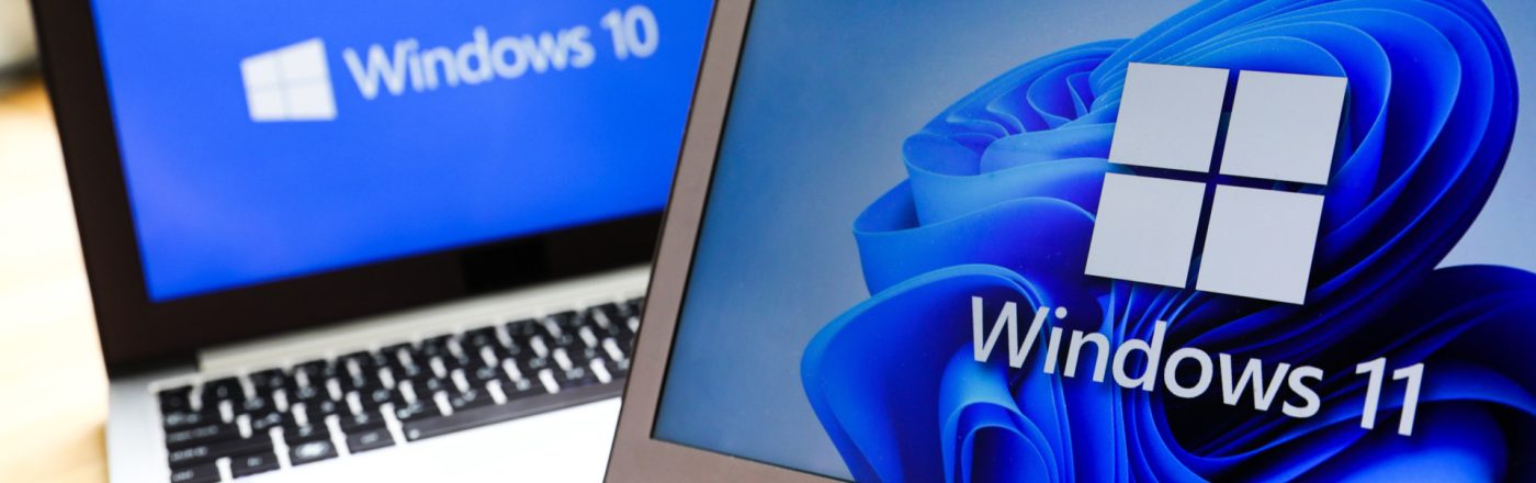 Zwei Notebooks, das im Hintergrund mit dem Logo von Windows 10, das im Vordergrund mit dem Logo von Windows 11