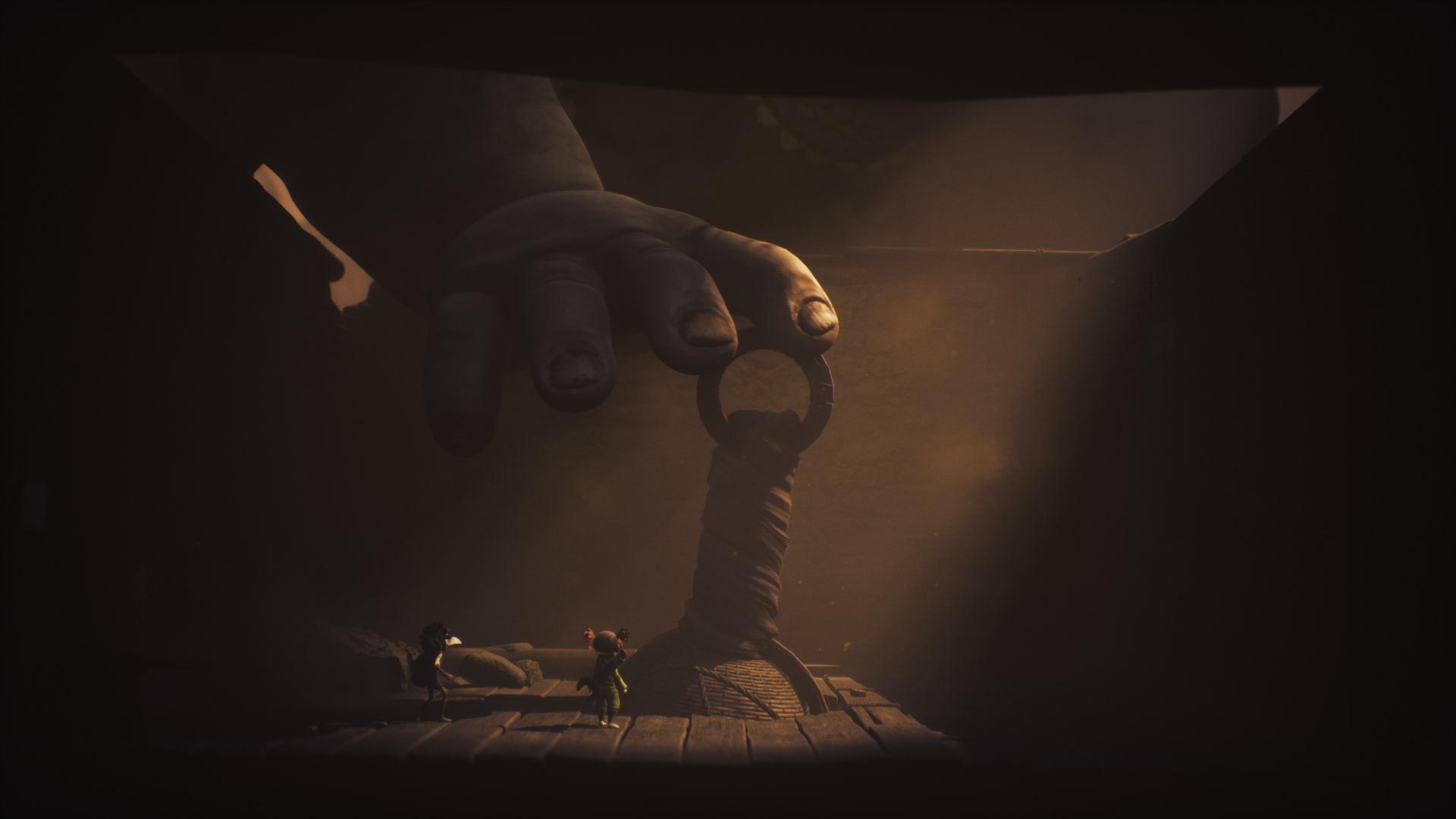 In der Szene aus dem Little Nightmares 3-Tipps-Artikel stehen Low und Alone einem gigantischen Gegner gegenüber: dem Riesenbaby. Die Kinder wirken winzig im Vergleich zu der riesigen Hand, die nach einem Seilring greift.
