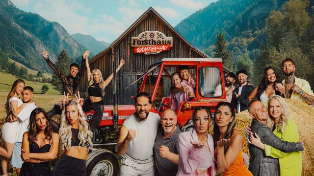Auf dem Gruppenbild zur Show Forsthaus Rampensau Germany stehen vor einer alpinen Holzhütte zahlreiche Kandidat*innen, darunter Melina Hoch mit Max Bornmann, Eva Benetatou, Walentina Doronina, Leon.Content, Gina Beckmann, Maurice Dziwak mit Vater Frank, Yeliz Koc, Dilara Kruse, Paul Aubster, Oliver Gaukel, Christo, C-Bas, Marc Robin Wenz, Henna, Bernhard Schwendemann und Sarah Knappik. Die Stimmung ist ausgelassen und voller Vorfreude.