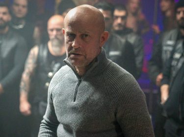 Jürgen Vogels Robert steht mit dem Rücken vor den Männern eines Motorradclubs.