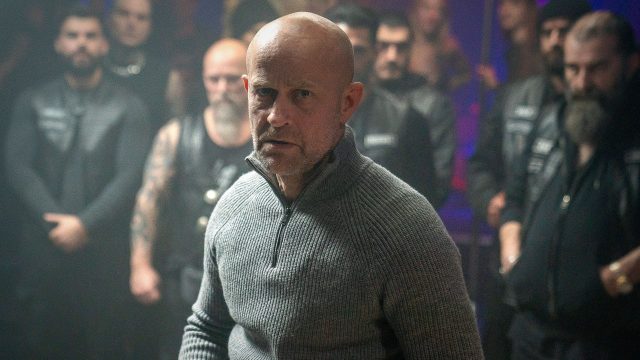 Jürgen Vogels Robert steht mit dem Rücken vor den Männern eines Motorradclubs.