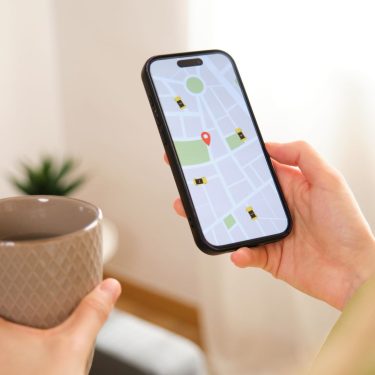 Frau mit Tasse in der Hand schaut auf die Navigations-App auf ihrem iPhone.