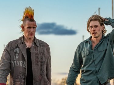 Auf dem Bild in den GigaTV-Highlights im November 2025 siehst Du eine Szene aus dem Film „Caught Stealing“. Austin Butler und Matt Smith laufen nebeneinander. Smith trägt eine auffällige Jacke mit Punk-Schriftzügen und einen orange-gelben Irokesenhaarschnitt, während Butler ein grünes Hemd trägt und sich mit der Hand durch die Haare fährt.