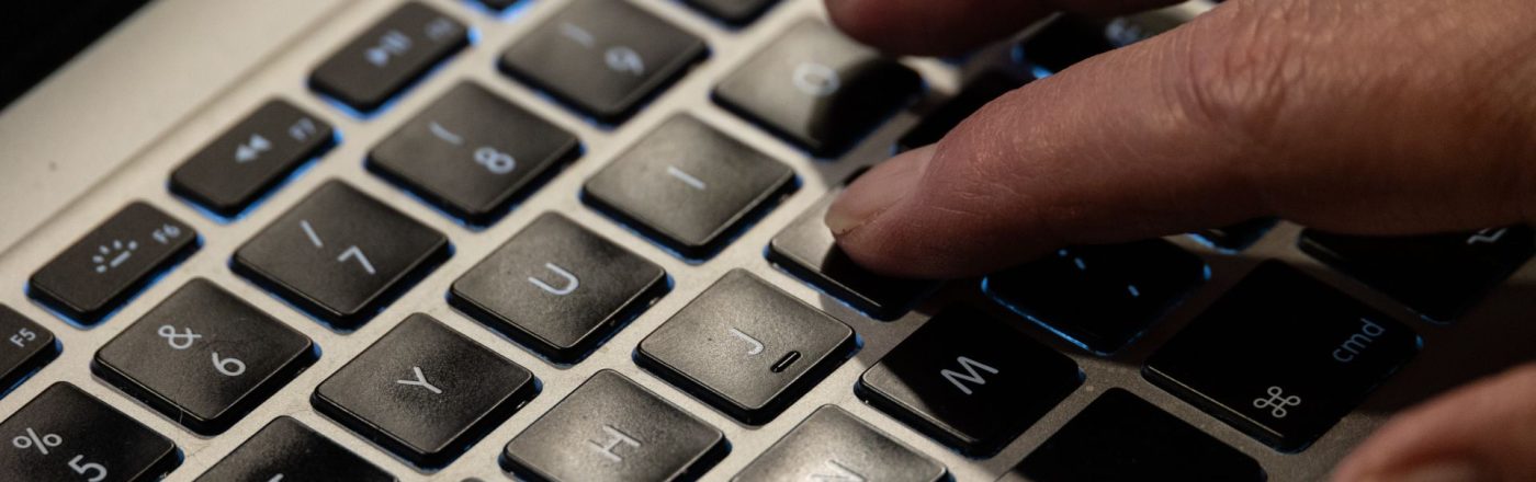 Jemand tippt mit seinen Fingern auf der Tastatur eines MacBooks.