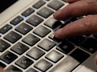 Jemand tippt mit seinen Fingern auf der Tastatur eines MacBooks.