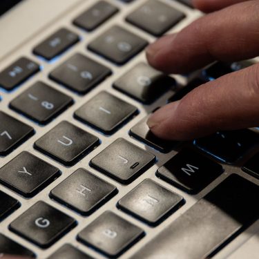 Jemand tippt mit seinen Fingern auf der Tastatur eines MacBooks.