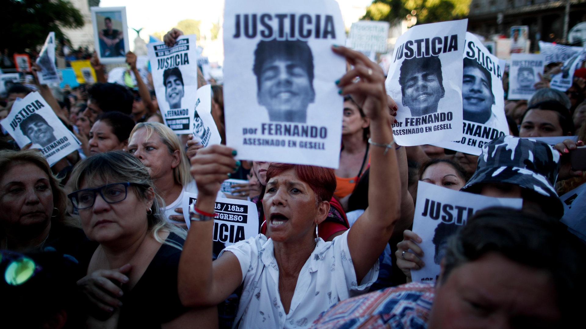 Menschen protestieren vor dem argentinischen Parlamentsgebäude und halten Plakate hoch.