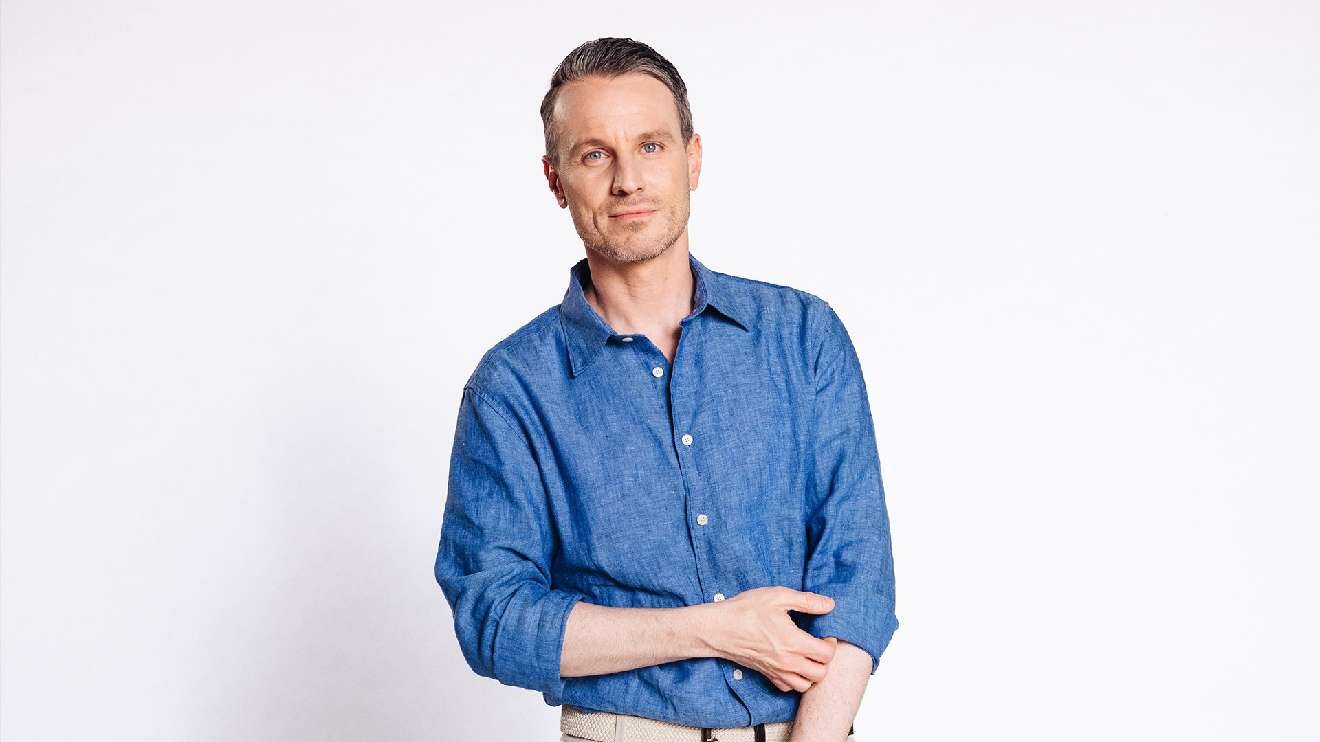 Auf dem Bild zur Alles was zählt Besetzung ist Schauspieler Marc Dumitru zu sehen, der in der Serie die Rolle von Kilian Reichenbach übernimmt. Er trägt ein hellblaues Leinenhemd und blickt ruhig und selbstbewusst in die Kamera. Mit neutralem weißen Hintergrund steht der Fokus ganz auf seiner Pose und seinem Gesichtsausdruck.