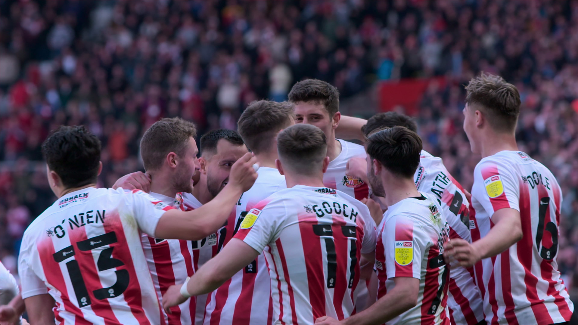 In der Doku-Serie „Sunderland 'Til I Die“ begleiten Zuschauer hautnah den englischen Traditionsklub. Auf dem Bild feiern mehrere Spieler von Sunderland in ihren rot-weiß gestreiften Trikots einen emotionalen Treffer. Die Szene wirkt mitreißend und authentisch – ein perfektes Beispiel für mitreißende Fußball-Serien mit echtem Stadionfeeling.