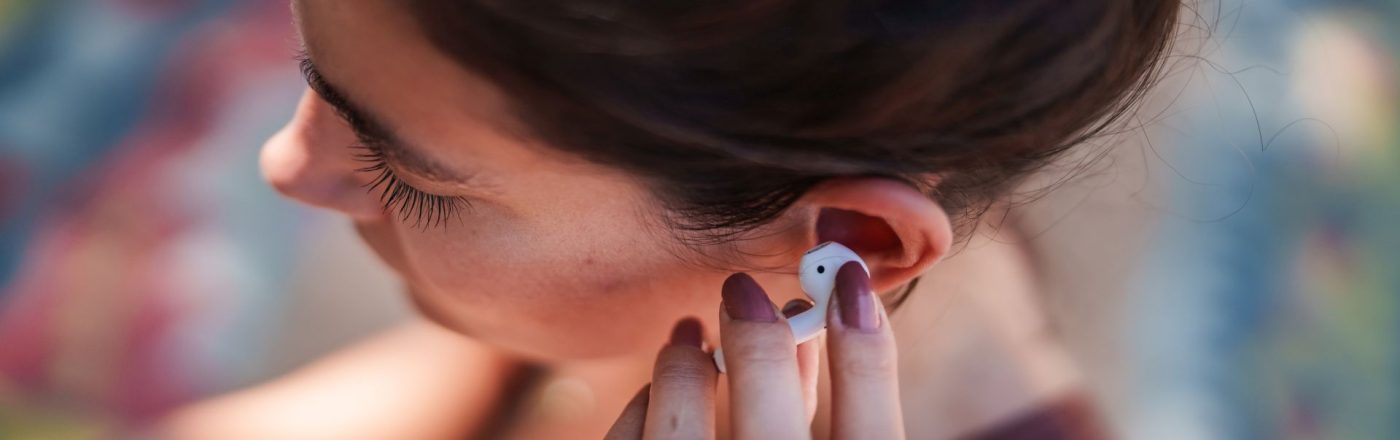 Frau legt sich die AirPods-Kopfhörer ins Ohr.