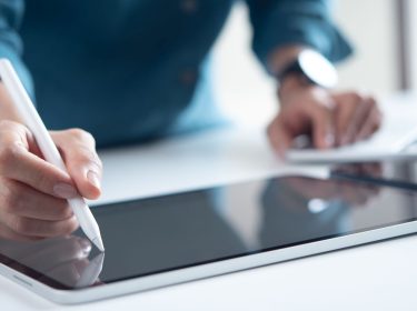 Mann schreibt mit Eingabestift auf seinem iPad-Display.