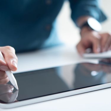 Mann schreibt mit Eingabestift auf seinem iPad-Display.