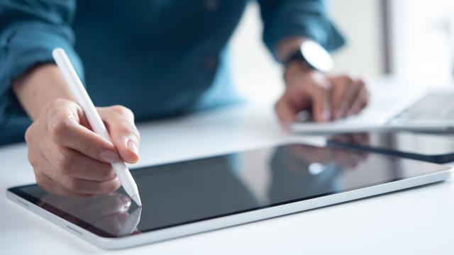 Mann schreibt mit Eingabestift auf seinem iPad-Display.