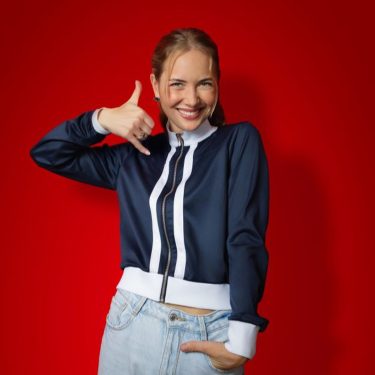 Auf dem Bild in dem Artikel zu den CallYa-Jahrespaketen und den Upgrades ist eine junge Frau vor rotem Hintergrund zu sehen. Sie trägt eine dunkelblaue Jacke und eine helle Jeans.