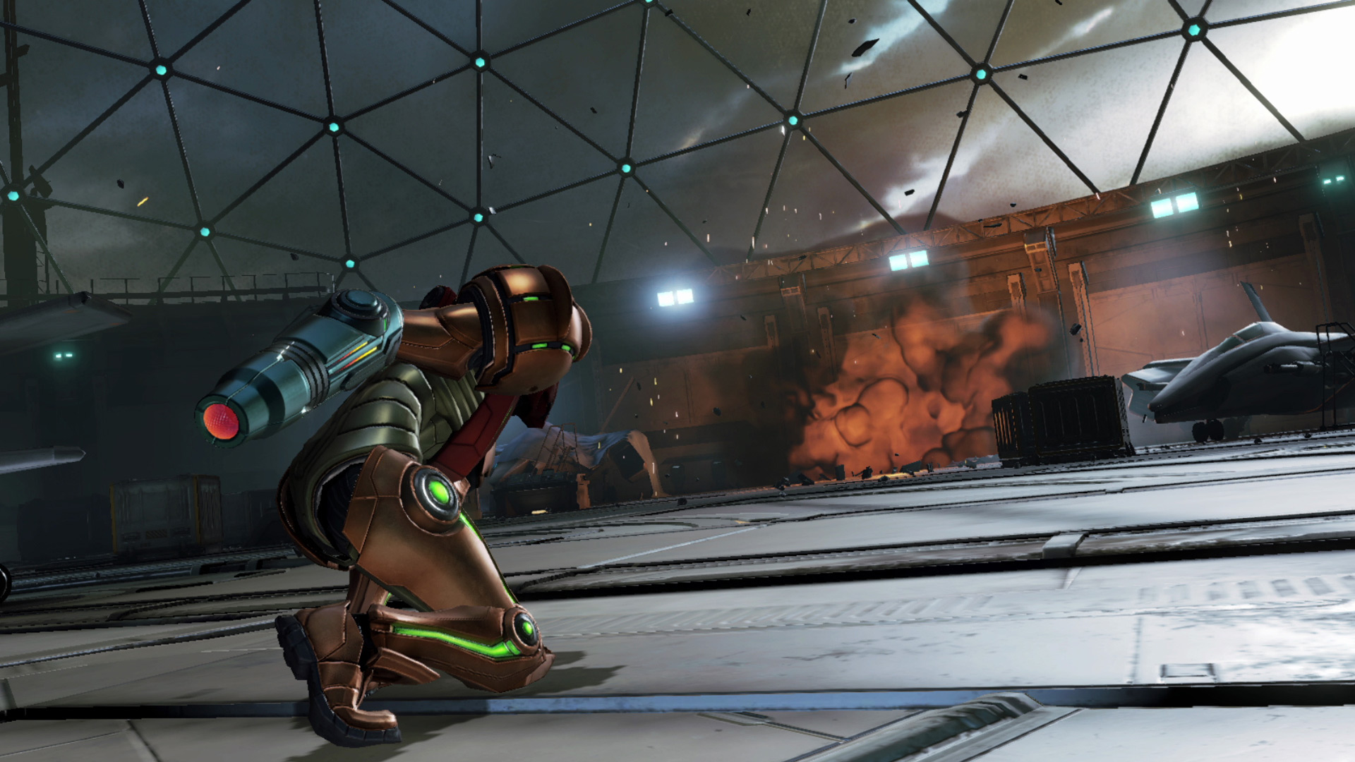 Im Bild zu Metroid Prime 4: Beyond Tipps kniet Samus Aran mit erhobenem Armkanone in einem futuristischen Hangar, während im Hintergrund eine Explosion für Chaos sorgt. Ihre Rüstung leuchtet an mehreren Stellen grün und wirkt kampfbereit. Trümmer und Flugzeuge verstärken die dramatische Atmosphäre der Szene.