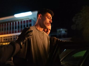 Koder Alian in Asbest: Polizei führt nachts einen jungen Mann in Handschellen zu einem Auto.