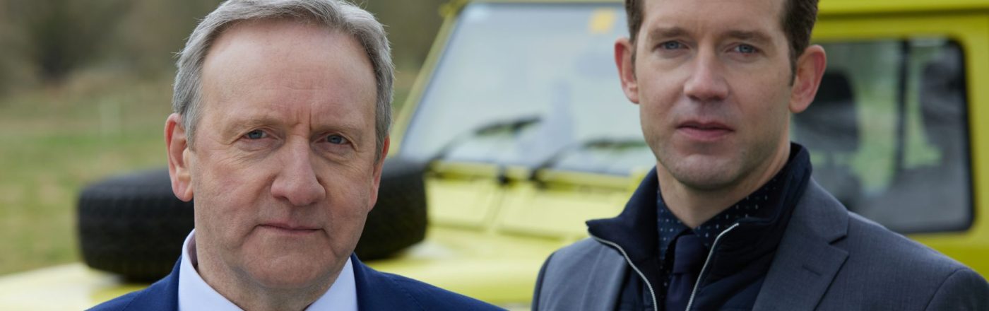 Neil Dudgeon als DCI Barnaby und Nick Hendrix als DS Winter stehen vor einem Auto in 