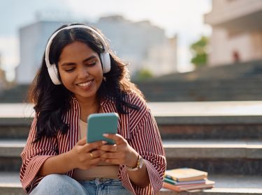 Auf dem Bild in dem Artikel zu den besten Hörbüchern 2025 laut BookBeat ist eine junge Frau mit langen dunklen Haaren mit Kopfhörern zu sehen.
