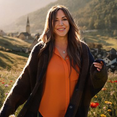 Simone Thomalla posiert für die Kamera auf einer Wiese.