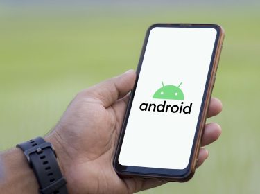 Ein Mann hält Smartphone hoch, auf dem das Android-Logo zu sehen ist