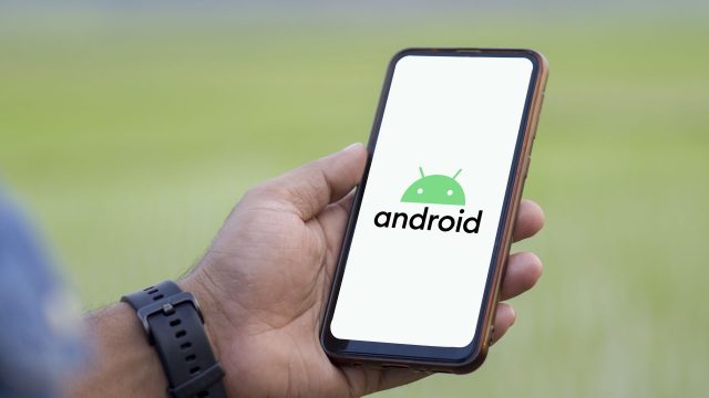 Ein Mann hält Smartphone hoch, auf dem das Android-Logo zu sehen ist