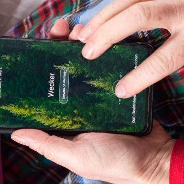 Hand schaltet Wecker auf dem Android-Handy aus.