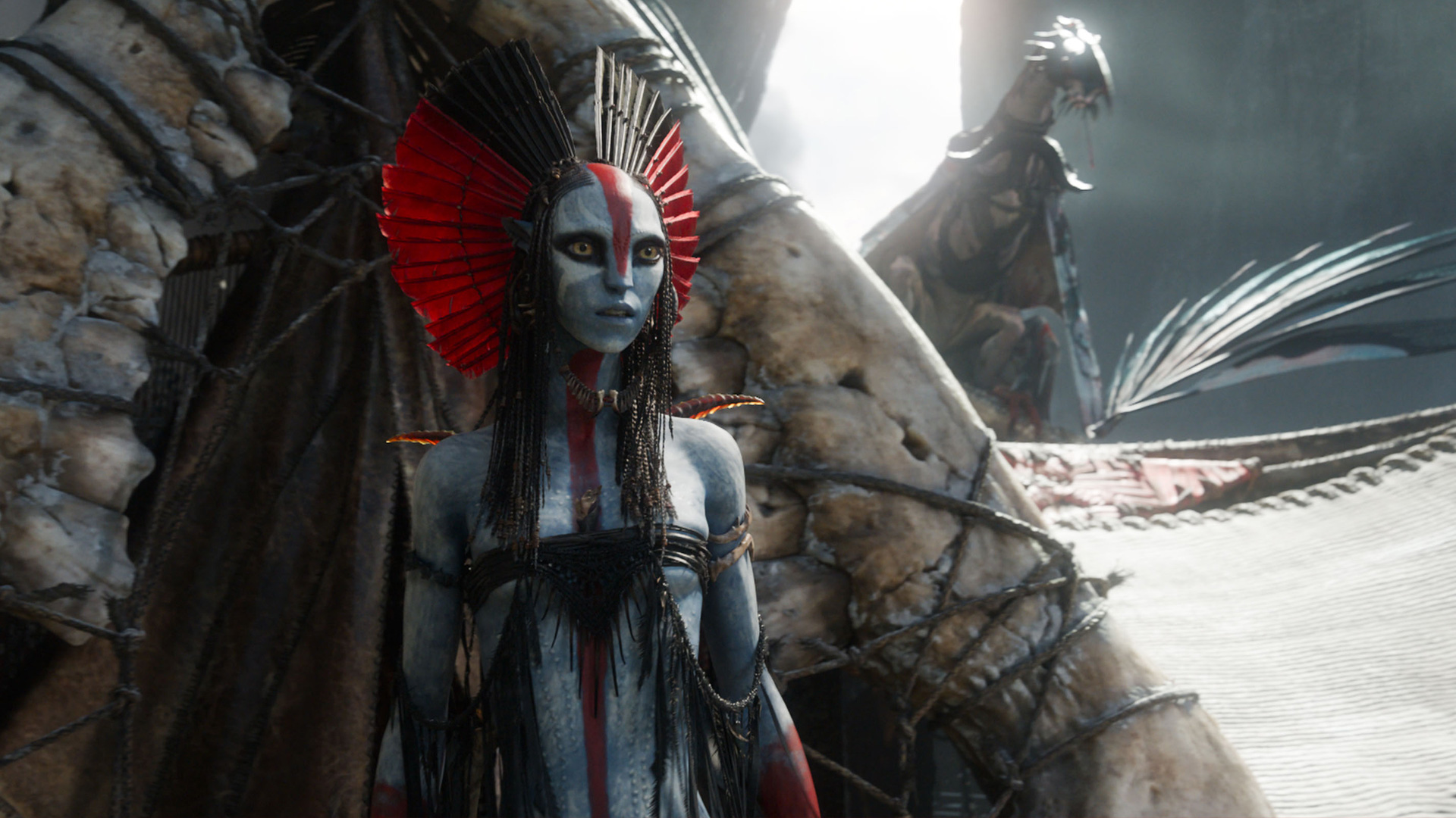 Im Bild aus Avatar: Fire and Ash ist die neue Figur Varang zu sehen, gespielt von Oona Chaplin. Sie steht ernst und aufrecht vor einer zeremoniellen Kulisse, geschmückt mit rotem Kopfschmuck und Kriegsbemalung. Ihre Präsenz wirkt autoritär und angriffslustig – eine zentrale Szene für die Avatar: Fire and Ash-Kritik.